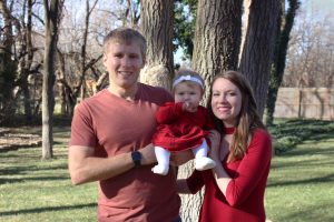 Image of Sarah and Thomas holding Baby Cecilia outside near trees