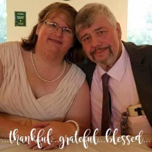 Image of Theresa and John smiling in pearls and a tie