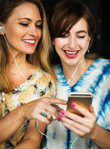 Image of women laughing at shared phone screen.