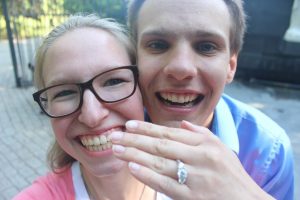 Image of Dominik and Lillian showing off her engagement ring with big smiles
