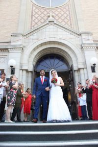 Image of couple standing outside a church in wedding clothes