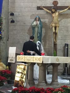 Image of couple praying in front of crucifix and Mary statue