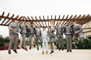 Image of groom and groomsmen jumping outside