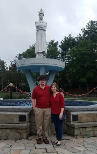 Image of a couple dressed in red in front of statue