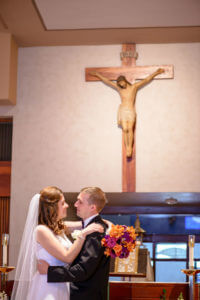 Image of couple on wedding day by crucifix