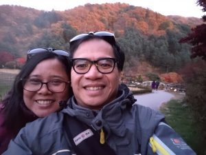 Image of couple taking selfie in front of colorful leaves