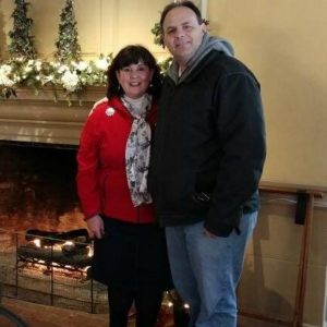 Image of couple near fireplace around Christmas time.