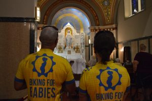 Image of couple in yellow shirts looking at Mayr statue