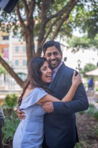Image of couple laughing and embracing outside. 