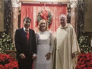 man and wife stand with priest