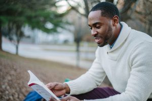 man reading book in park